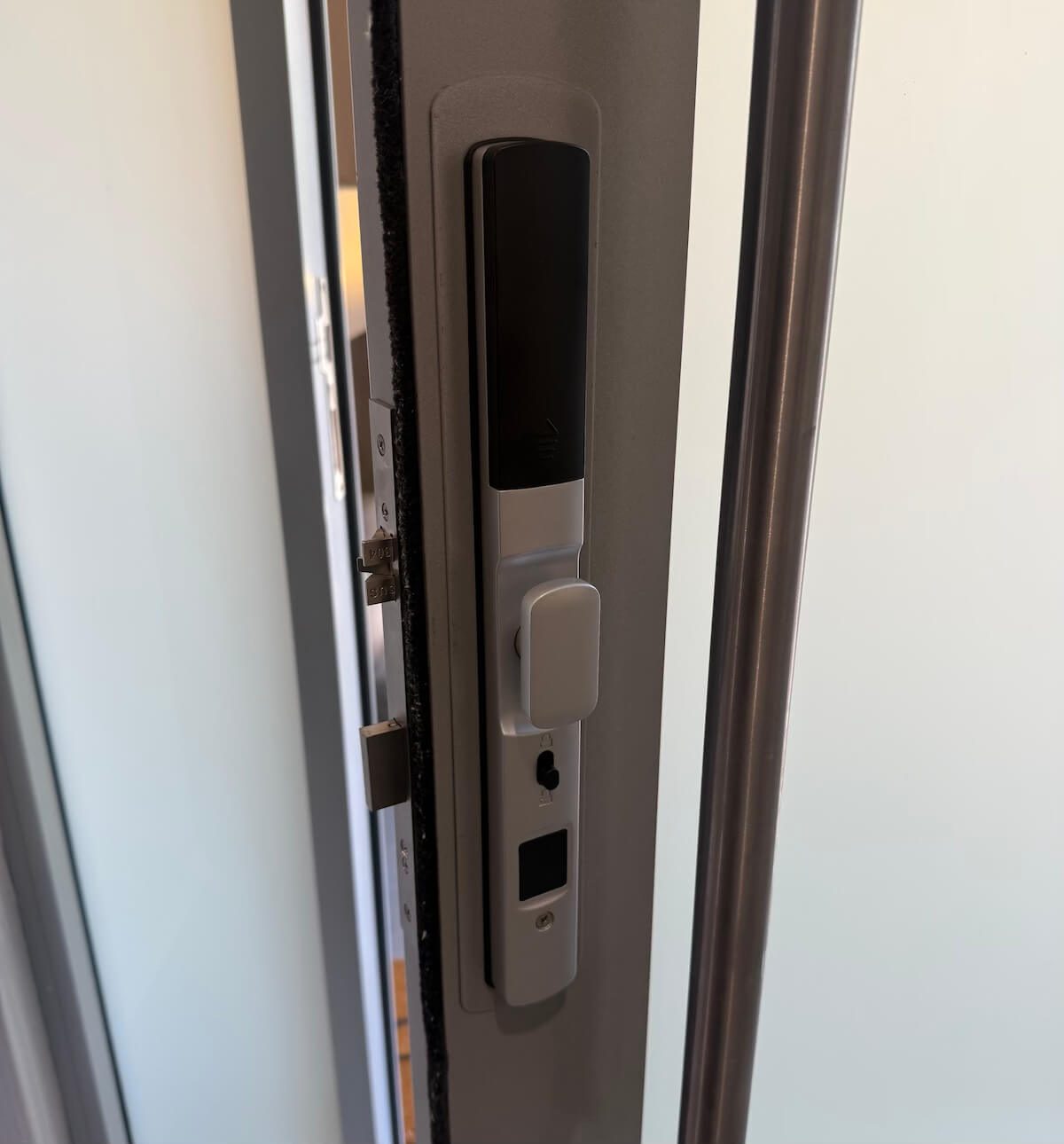 Close view of the silver short-handle smart door lock fitted to a white door