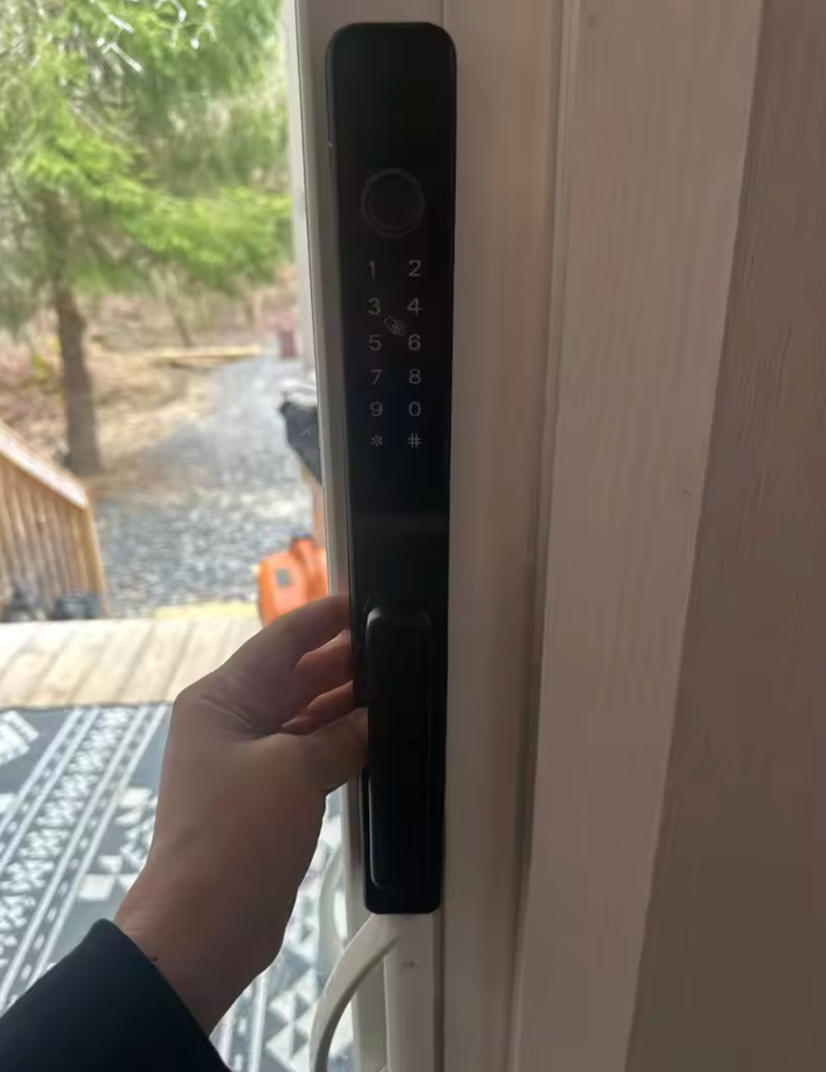Hand holding an RFID card to the keypad of the black short-handle smart door lock on an outdoor timber door