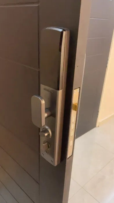 Inner panel of a smart door lock with thumbturn and locking knob, in a champagne gold finish, on a brown door
