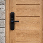 Black lever-handle smart door lock fitted to a timber front door beside a brick wall